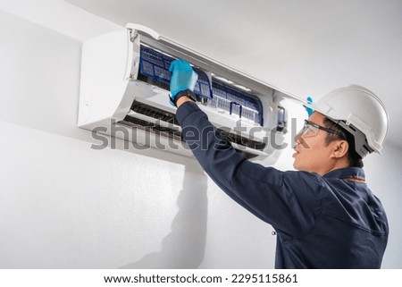 Air technician wear uniform service removing air filter of the air conditioner for cleaning on white wall. Service concept of an air conditioner technician. Royalty-Free Stock Photo #2295115861