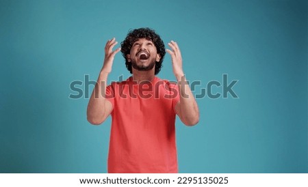 Extremely excited overjoyed latin spanish man with beard shouting making yes gesture, amazed with his victory, triumph on blue studio background Royalty-Free Stock Photo #2295135025