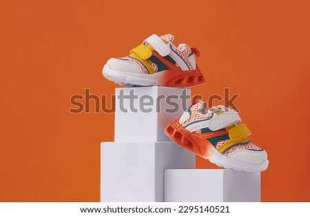 Baby sneakers, child sport shoes pair on color background. Fashion kids outfit. Fashionable sports shoes. Creative minimalistic layout with footwear mock up for your design. Advertising for shoe store