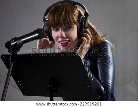 stylish female singer with microphone and reading lyrics