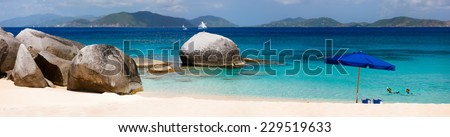 Panorama of a picture perfect beach with blue umbrella, white sand and turquoise ocean water at tropical island in Caribbean
