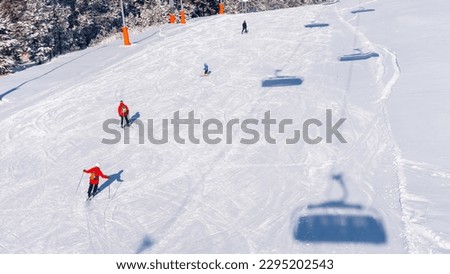 This captivating photo captures the thrill of snowboarding on an exhilarating slope, set against a breathtaking mountain backdrop. With snowboarders cutting through the white snow, this impressive ima