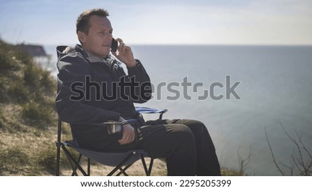 man drinking tea from a thermos on the sea
