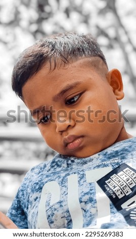 Boy looking down bored, nature background, garden. The concept of lazy, bored, thinking