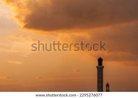 a tip of the pillar and dome of a mosque between the evening sky and sunset