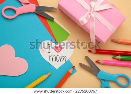 A child draws a postcard for mother's day. Beautiful landscape with mom drawn with pencils. Happy mother's day. Happy birthday card for mom. Top view