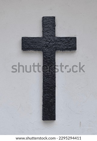Black christian cross set on a white wall