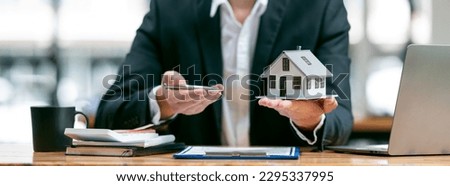Businessman or real estate agents holding house model offering to his client after signing the sale at the office.