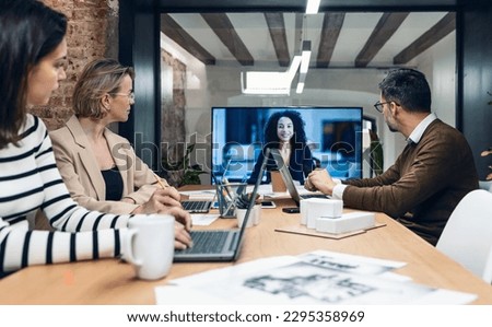 Shot of smart business people working and talking of they new project while doing a video call with company director in modern office Royalty-Free Stock Photo #2295358969