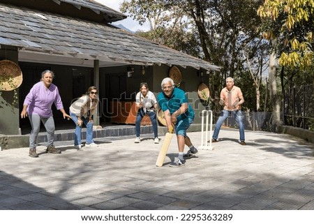 Family members playing cricket in the back yard.