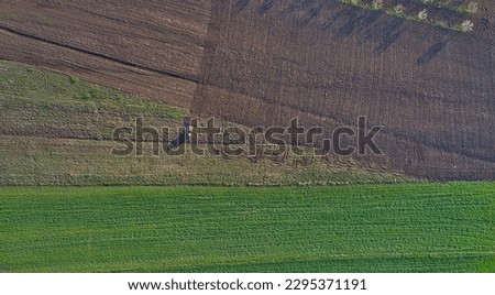 Top view from a drone on a green field and a tractor processing the field. Agriculture