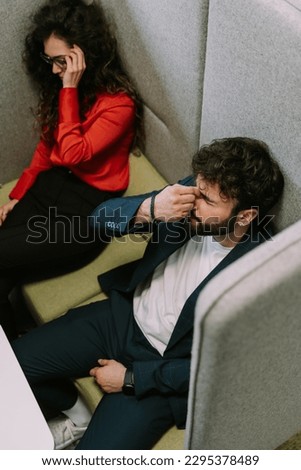 Lovely couple just woke up after they took a nap at work. The male is rubbing his eyes and his girl is putting her eyeglasses on. Above view photo