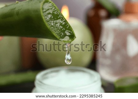 Aloe vera leaf with dripping gel against blurred background, closeup Royalty-Free Stock Photo #2295385245