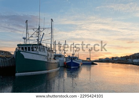 Fishing boats moored at the dock at sunset during the winter, Port de Grave, Newfoundland and Labrador, Canada. Royalty-Free Stock Photo #2295424101