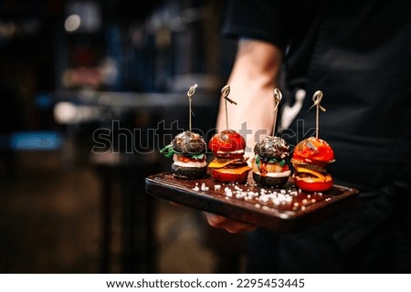 Waiter hold set mini hamburgers, mini burgers on plate in restaurant Royalty-Free Stock Photo #2295453445