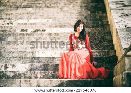 Girl sitting on a stairs in a red dress