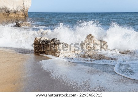 Large rock sticking out of the ocean next to a beach