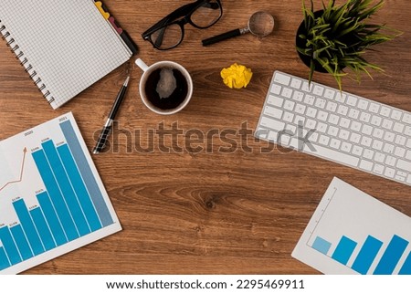A photo top view of office desk with growth chart and keyboard
