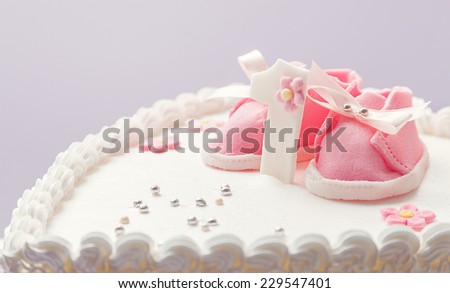 Details of a birthday cake for baby girl, number one and sweet sugar shoes on top. 