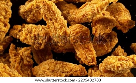 Fried chicken pieces flying up in the air. Realistic freeze motion shot. Royalty-Free Stock Photo #2295482783