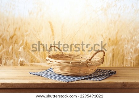 Empty wooden basket on table with tablecloth over wheat field background.  Jewish holiday Shavuot mock up for design and product display. Royalty-Free Stock Photo #2295491021