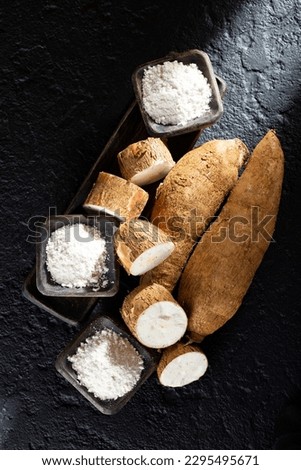pile of cassava and cassava flour on dark background (Manihot esculenta)