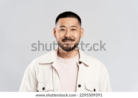 Smiling Korean male looking at camera isolated on gray background. Handsome young guy standing in studio, posing for picture