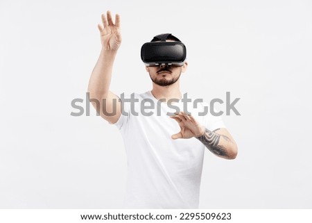 Pensive asian man in casual clothes wearing VR glasses playing video game isolated on white background. Attractive young student standing and using modern technology