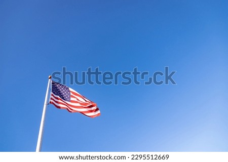 A picture of an American flag under a blue sky.
