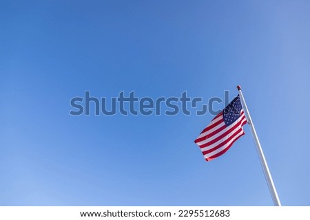 A picture of an American flag under a blue sky.