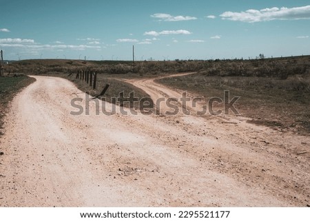 A ramification Country dirt road diverges in two directions - to a right, to a left. Life choices, uncertainty concept. Routes, walkways, trails. Spanish landscape. Two narrow paths Divergence of path Royalty-Free Stock Photo #2295521177