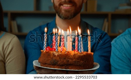 Close up festive cake with burning candles happy bearded unrecognizable birthday man smiling make wish celebrate event with friends at home party celebration anniversary year tradition congratulation
