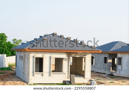  Village construction project Single house which is in the process of building a house with prefabricated concrete slabs and is covering the roof with tiles unfinished in the summer of Thailand. Royalty-Free Stock Photo #2295558807