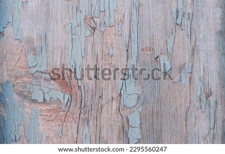 The view on the rustic rough surface of the   wooden wall with cracks, scratches, and peeling off the old li paint remains