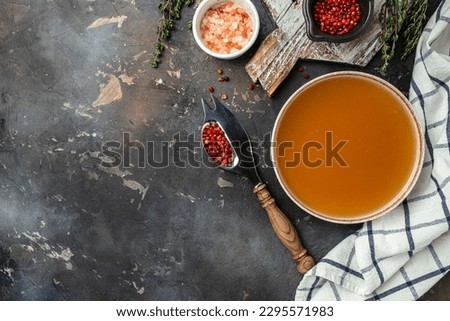 Bone Broth Bouillon in bowl with herbs and spices on a dark background, banner, menu, recipe place for text, top view.