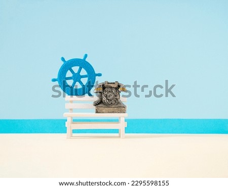 Rudder ship, bench, and phone on summer background. Minimal concept of traveling, summertime, booking, joyful, sea horizon. Copy space. Frontal view.