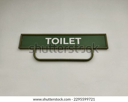 green "Toilet" sign on a white wall