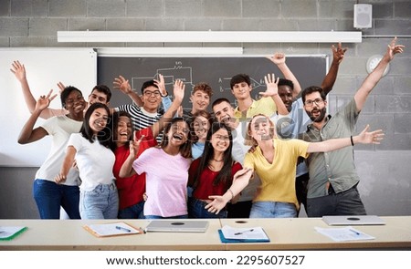 Portrait of a cheerful group of students celebrating in class looking at the camera. Happy Young college people of different ethnicities posing for a photo in the classroom hands up High quality photo