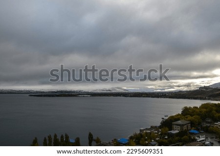 Beautiful autumn view of Sevan lake with dark water and snow-capped mountains. Natural scenery of Armenia