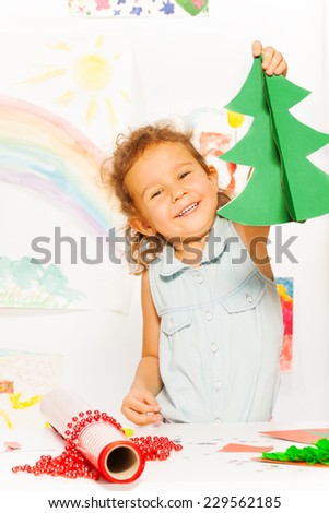 Positive girl holds carton Xmas tree standing
