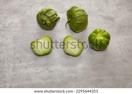 Mexican husk tomatoes also known as green tomatillos with the husk, whole without husk and cut in half.