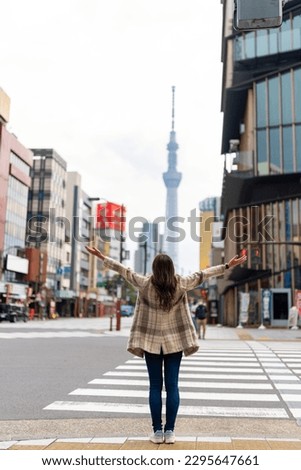 Asian woman shopping and crossing street crosswalk with crowd of people at Asakusa district, Tokyo, Japan in autumn. Attractive girl  enjoy and fun outdoor lifestyle travel in city on holiday vacation