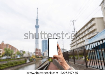 Asian woman using mobile phone taking picture cityscape and urban building in Tokyo city, Japan in autumn. Attractive girl enjoy outdoor lifestyle walking and travel city street on holiday vacation.