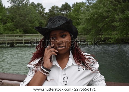A gorgeous plus-sized model of African descent using her cell phone, engaged in a coversation Royalty-Free Stock Photo #2295656191