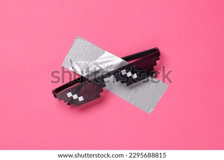 Pixel sunglasses fixed with adhesive tape on a pink background. Conceptual pop, contemporary art, minimalist still life Royalty-Free Stock Photo #2295688815