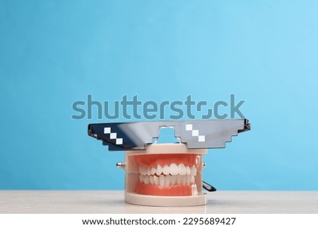 Human jaw model with pixel sunglasses on blue background
