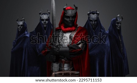 Portrait of four members of dark cult and their leader with sword. Royalty-Free Stock Photo #2295711153