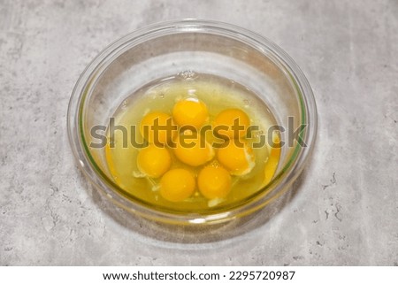 Eight whole eggs (egg whites and yolks) with no shells in a glass bowl.
