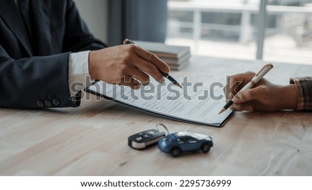Closeup asian male people car salesman or sales manager offers to sell a car and explains and reads the terms of signing a car contract and insurance. Royalty-Free Stock Photo #2295736999