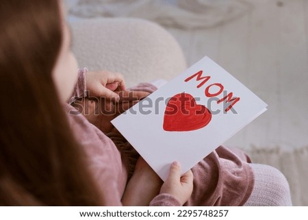 Happy mother's day. Child daughter congratulating her mother and giving her postcard.